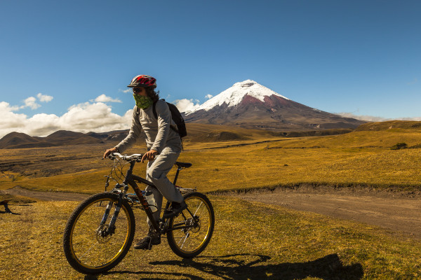 Turista masculino realizando ciclismo de montaña en el Parque Nacional Cotopaxi en un día soleado