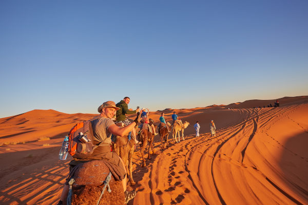 Grupo de turistas recorriendo el desierto del Sahara en Marruecos sobre camellos