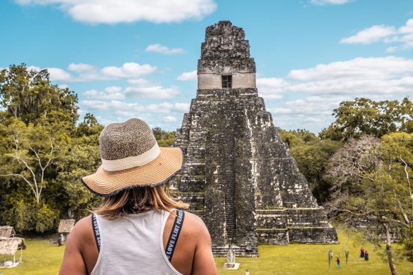 Mujer turista con sombrero admirando el Templo del Gran Jaguar en la Gran Plaza de Tikal, Guatemala.