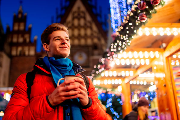 Turista con bebida caliente en el mercado navideño de Wroclaw, Polonia