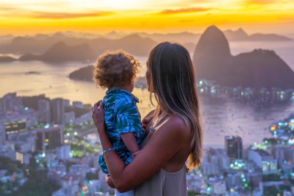 Madre e hijo en un mirador de la ciudad de Río de Janeiro, Brasil, contemplando el Pan de Azúcar al atardecer.