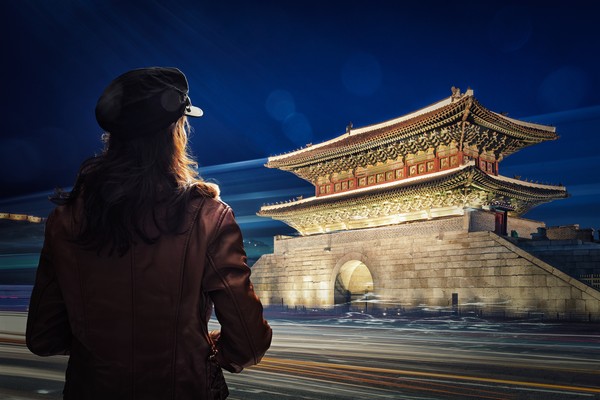 Mujer turista mirando la Puerta de Heunginjimun por la noche en la ciudad de Seúl, Corea del Sur.