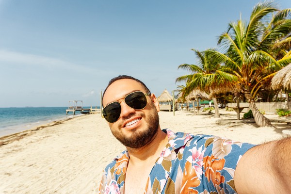 Hombre turista feliz tomando selfie en la playa de Guanaja, Honduras.