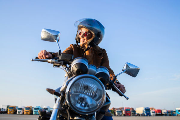 mujer feliz sobre una motocicleta en plena ruta.