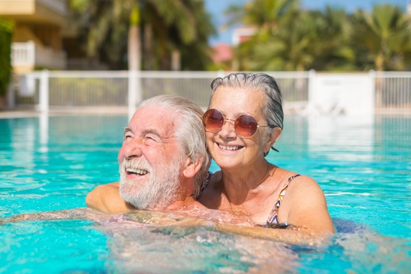 Pareja de adultos mayores disfrutando juntos de una piscina en sus vacaciones.