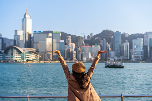Joven viajante relajándose y disfrutando de la atmósfera de puesta de sol en el puerto Victoria en Hong Kong. Seguro de viaje Asia.