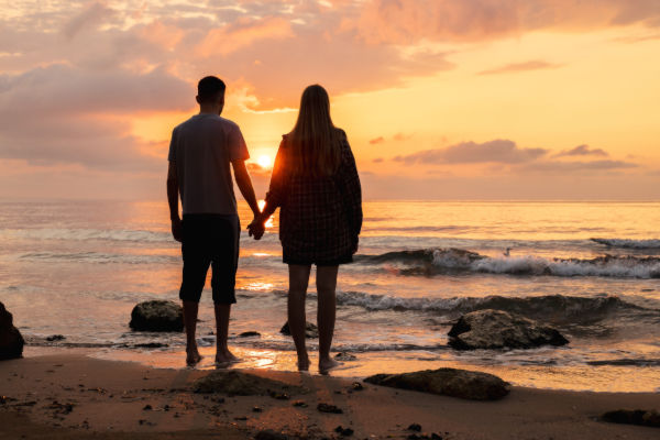Pareja contemplando el atardecer en una playa de Aruba, un viaje soñado para disfrutar con tranquilidad.