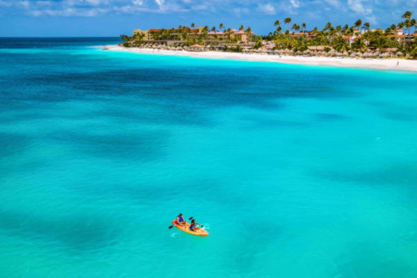 Pareja en kayak sobre el mar cristalino de Aruba, destino ideal para unas vacaciones desde Colombia.