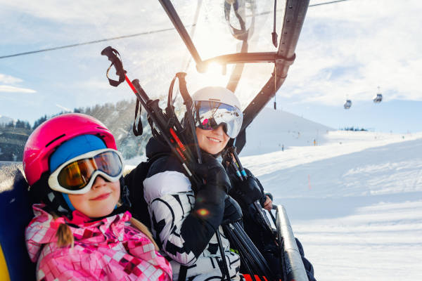 Madre e hija disfrutando de vacaciones de esquí de invierno en las montañas alpinas austriacas, a salvo gracias a más que un seguro de viaje Austria.