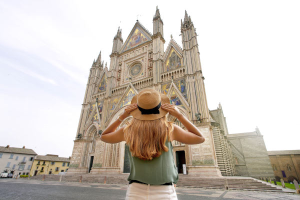 Joven turista con sombrero contemplando la Catedral de Orvieto, Umbría, Italia.