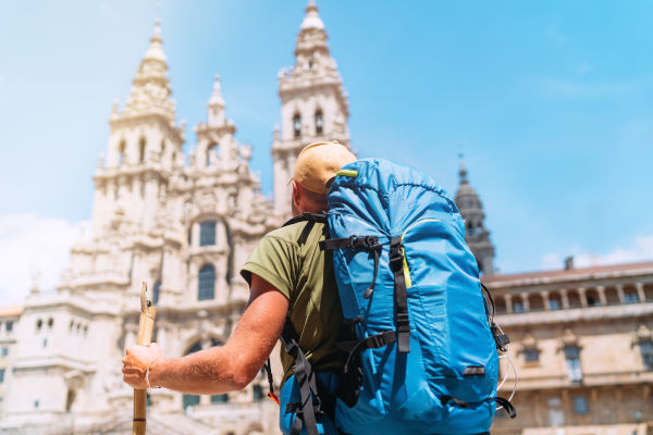 Peregrino con gorra y mochila llegando a la Catedral de Santiago de Compostela.