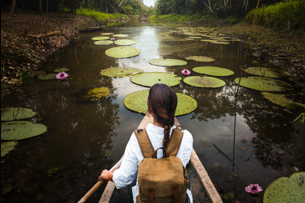 Mujer con mochila remando en una canoa por el río Amazonas.