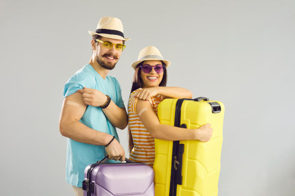 pareja sonriendo mostrando sus vacunas antes de viajar.