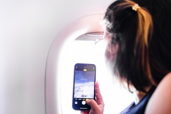 Mujer latina toma fotos a través de la ventana del avión.