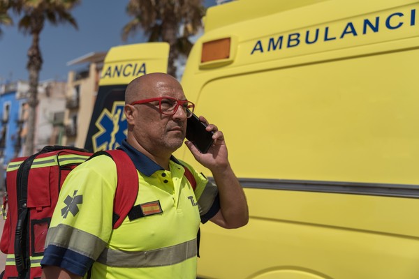 Paramédico español en las calles junto a la ambulancia hablando por teléfono.