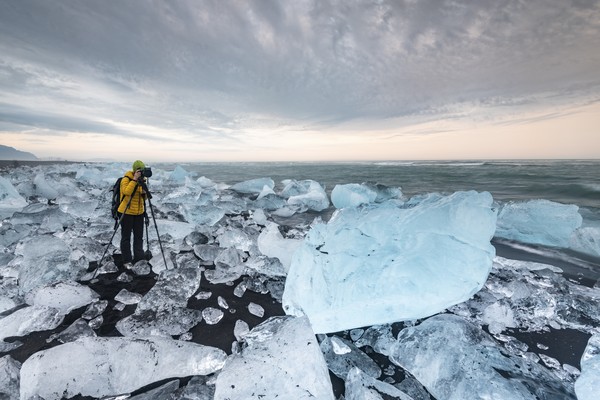 Fotógrafo en Diamond Beach, con icebergs en la playa de lava negra, cerca de la laguna glaciar Jökulsarlon, Parque Nacional Vatnajökull, Hornafjörður, sur de Islandia.