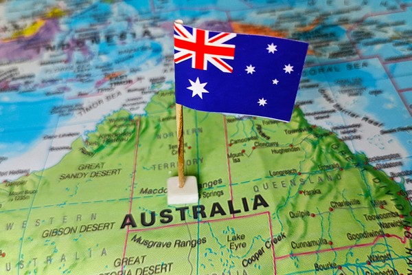 Bandera de Australia sobre un mapa físico político del país.