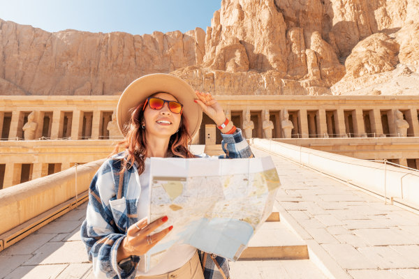 Mujer viajera con un mapa físico, explorando los lugares de interés cerca del Templo de Hatshepsut, Alto Egipto