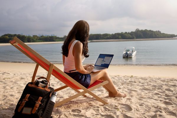 Mujer estudiando con su laptop en la playa.