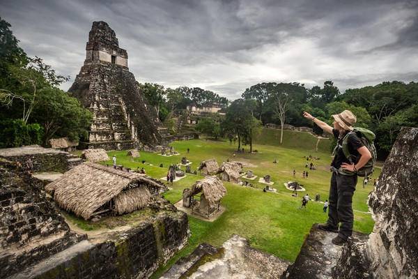 Turista señalando desde una altura la famosa pirámide Tikal en un día nublado en Guatemala.