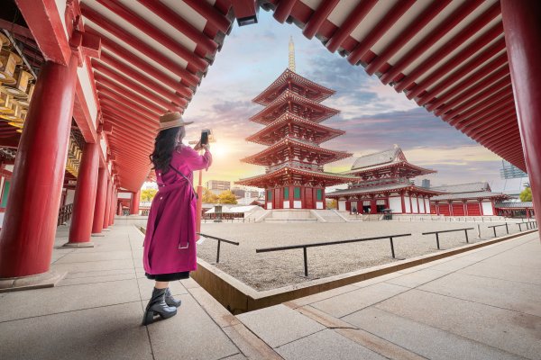 Mujer turista, que cumple con los requisitos para viajar a Japón desde Ecuador, tomando una foto de un templo en Osaka, Japón.
