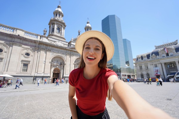 Mujer turista tomándose una selfie en Plaza de Armas, Santiago de Chile, en un día soleado.