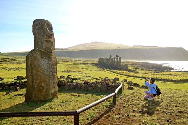 Mujer turista tomando una fotografía de un Moai en Ahu Tongariki, Isla de Pascua, Chile
