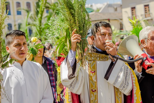 Sacerdote con megáfono predicando en una celebración del Domingo de Ramos en Quito, Ecuador.