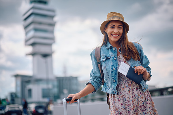 una mujer feliz con una valija y un pasaporte en su mano