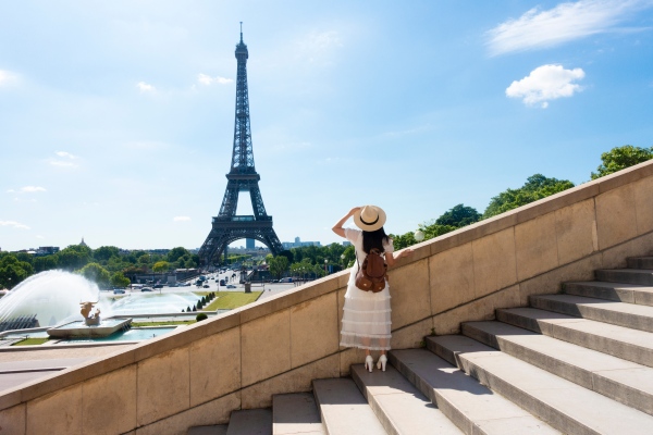 Mujer parada en escaleras apreciando la Torre Eiffel en París.