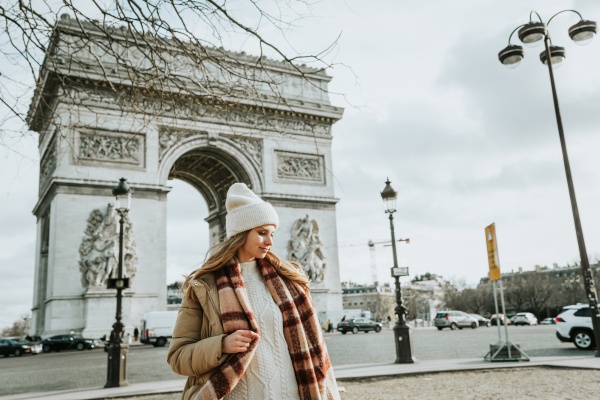 Mujer abrigada frente al Arco del Triunfo en París.