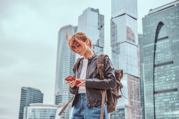 Mujer de viaje que usa su celular para contactar a su seguro de viaje internacional.