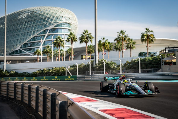Coche de Fórmula 1 en el Circuito Yas Marina en Abu Dhabi en un día soleado con palmeras y arquitectura exterior del hotel Yas Marina de fondo.