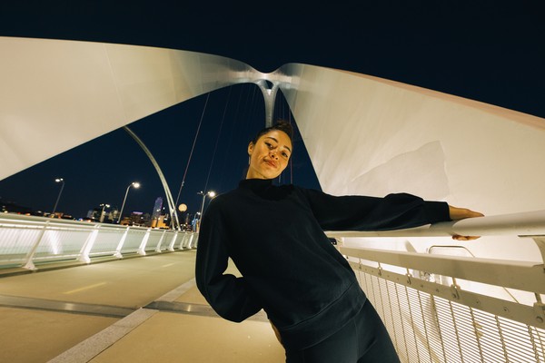 Mujer posando para la foto tomada de la barandilla de un puente en Oak Cliff, Dallas, Texas, por la noche.