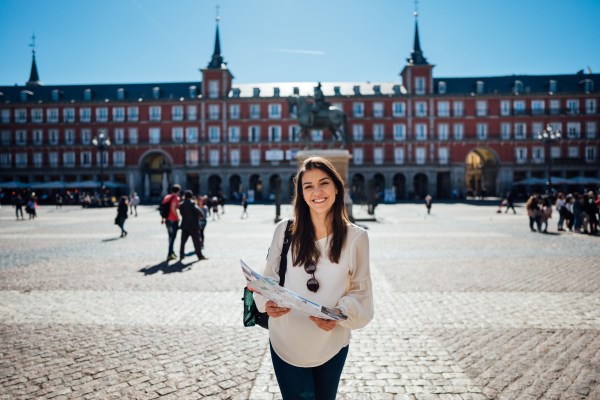Mujer turista que cumple con los requisitos para viajar a España, usando un mapa para guiarse en la Plaza Mayor, en Madrid.