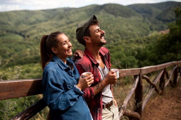 Pareja bebiendo una taza de café en un sendero al aire libre.