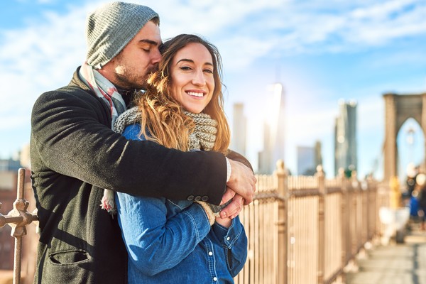 Pareja feliz en un puente de Nueva York en un día soleado.