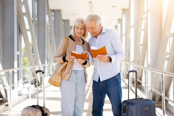 Pareja de adultos mayores revisando sus pasaportes en un aeropuerto.