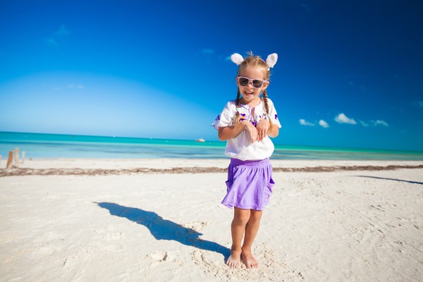 Niña con orejas de conejo posando para una foto en una playa exótica durante un viaje en Pascuas, Semana Santa.