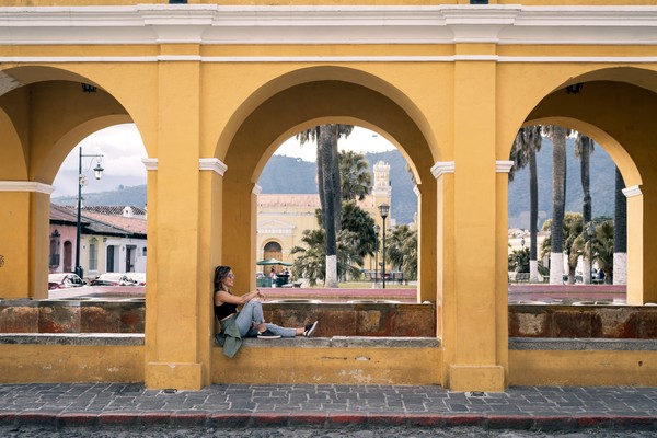 Viajera sentada en unos arcos coloniales en Antigua Guatemala.