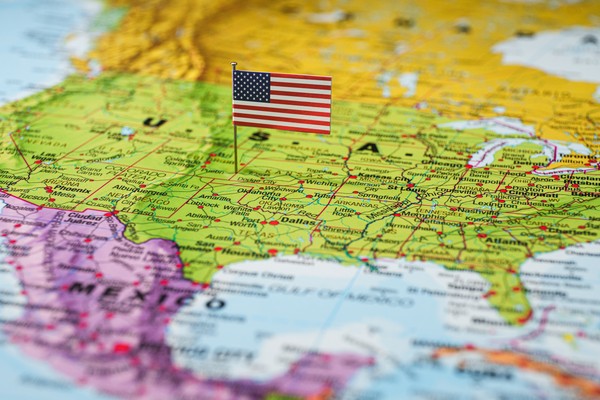 Bandera de Estados Unidos de América en miniatura clavada sobre un mapa físico político de Norteamérica