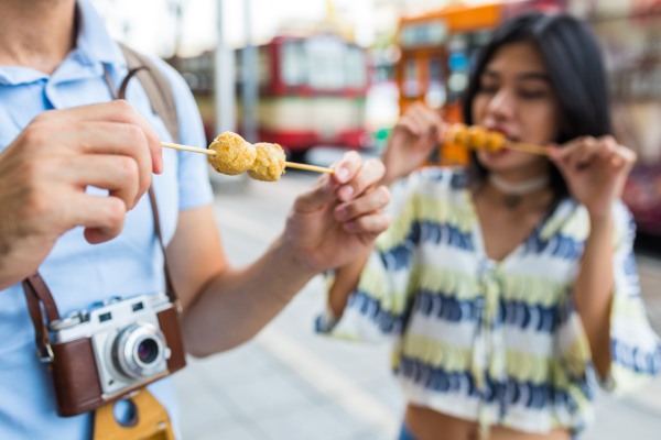 Turistas comiendo comida callejera como parte del turismo gastronómico.