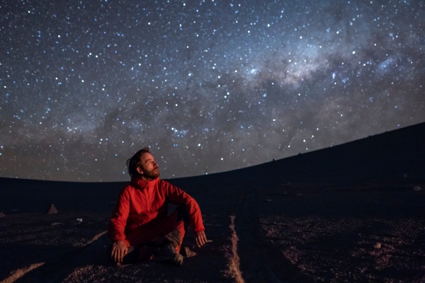 Hombre observando el cielo en el desierto de Atacama de noche.
