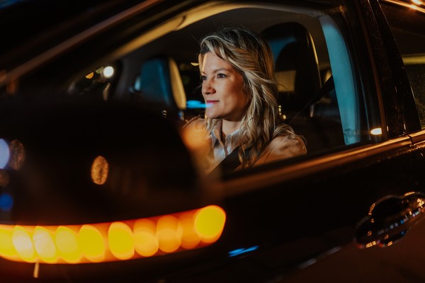 Mujer conduciendo el coche por la noche en la ciudad.