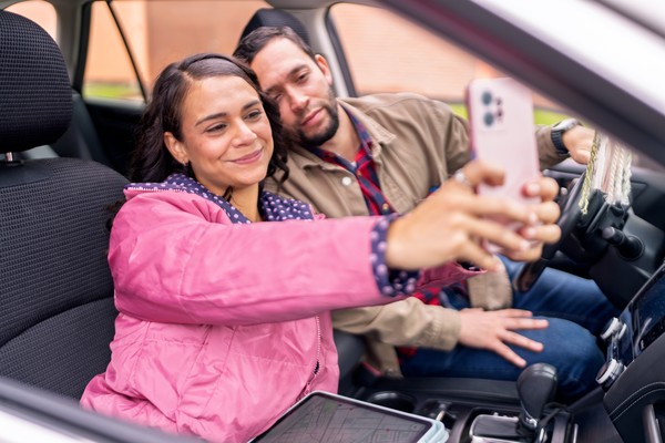 Pareja tomándose una selfie dentro de un coche mientras viajan.
