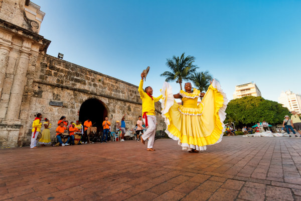 Pareja de jóvenes vestidos de amarillo bailando fandango en una de las entradas a la ciudad amurallada de Cartagena, Colombia.