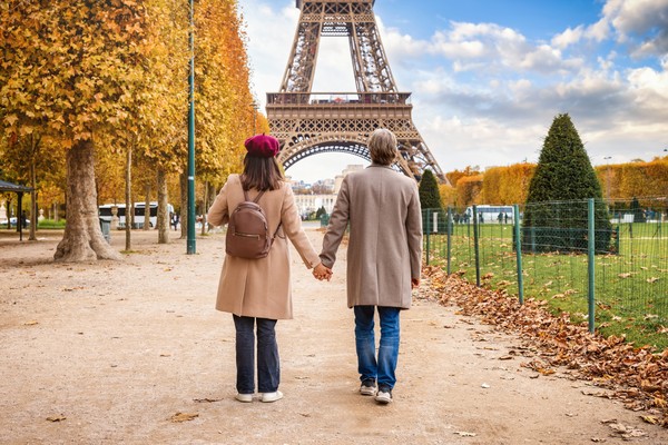 Pareja caminando por un parque en las cercanías de la Torre Eiffel de París en otoño.