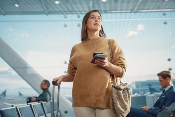 Mujer con maleta y documentos en la mano en el aeropuerto, lista para abordar