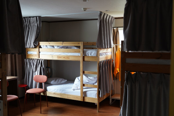 Camas tipo literas de madera con cortinas grises en albergue juvenil en Tokio, Japón.