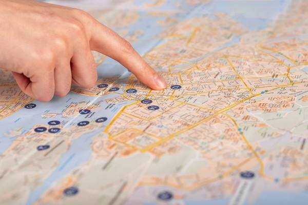 Dedo señalando distintos puntos en un mapa de la ciudad con números identificativos de posibles atracciones turísticas.